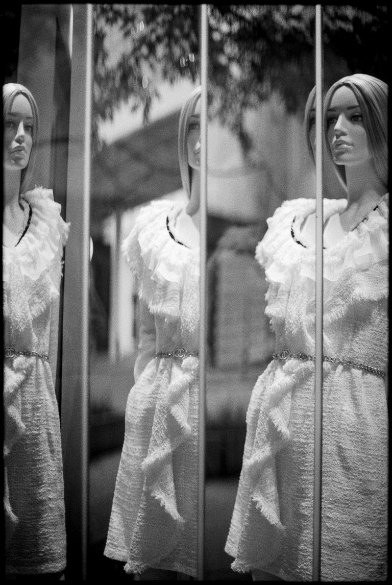 A mannequin endlessly examines facets of herself in a series of tilted mirrors.