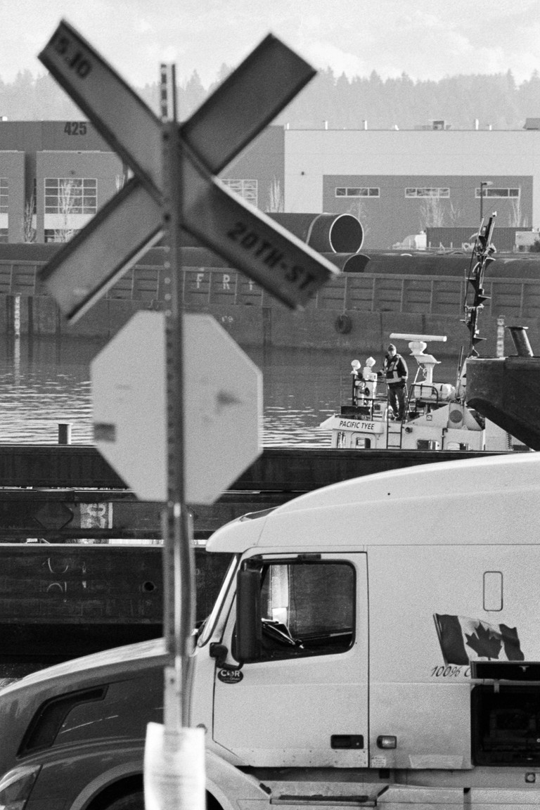 A tugboat crew member peers out in a layered industrial scene.