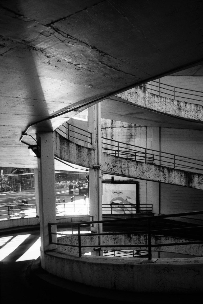 Amidst a grimy urban scene a billboard projects the image of a woman eating a single strawberry.