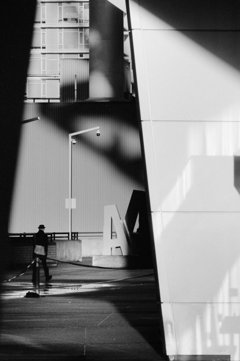 A man in a hat walks toward an unusual collection of geometric shapes and letters