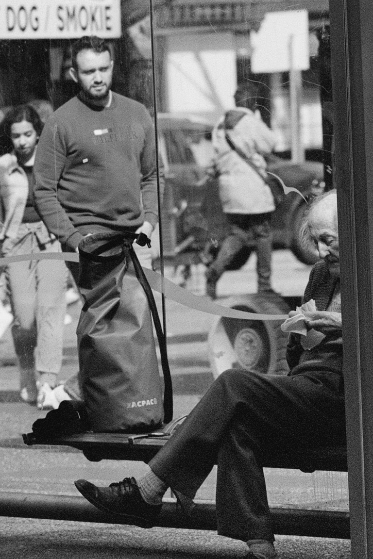 Pedestrians moved in separate directions while a man quietly considers his sandwich.