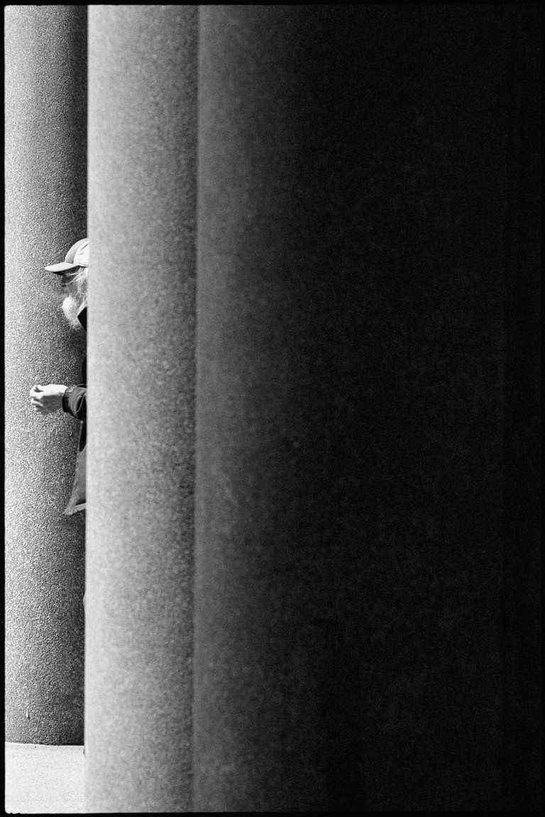 A smoker, in profile and partially obscured, observes happenings.