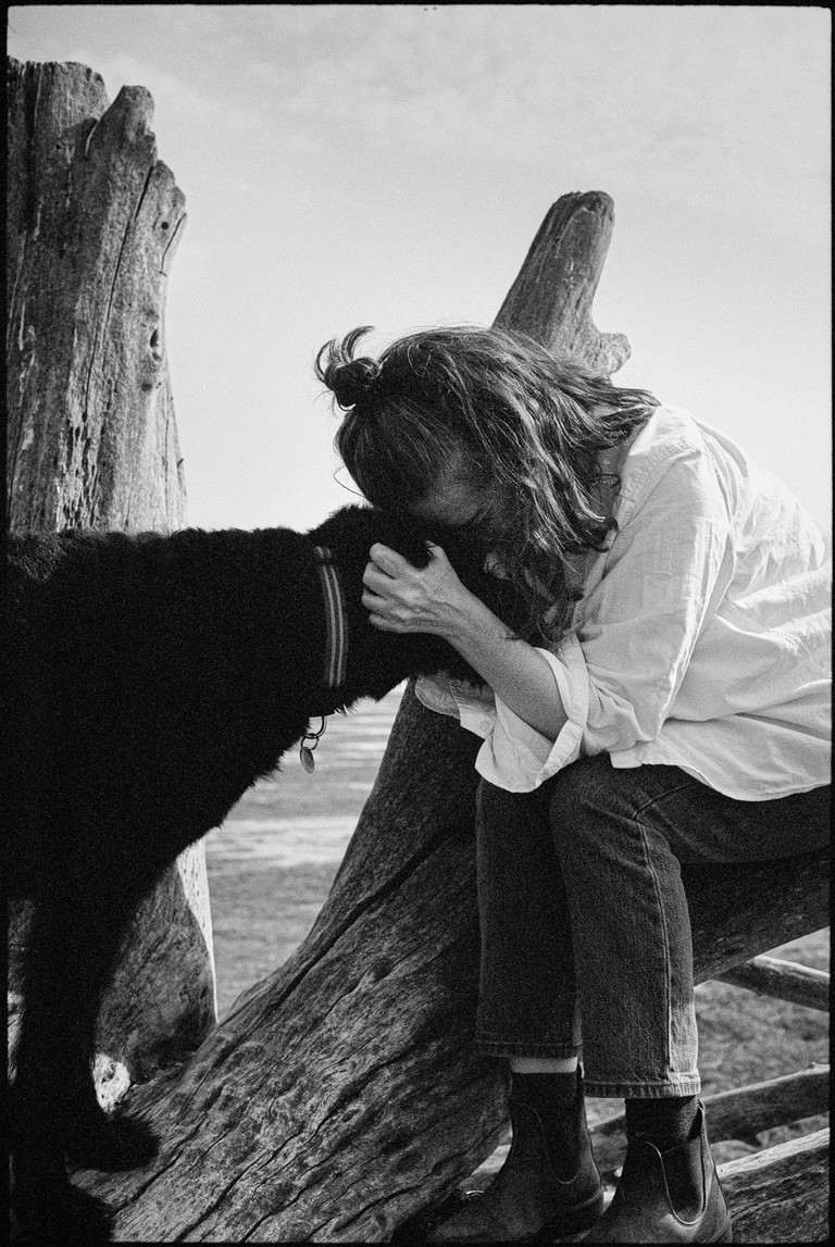 A woman and her talk have a quiet moment together on a rugged beach