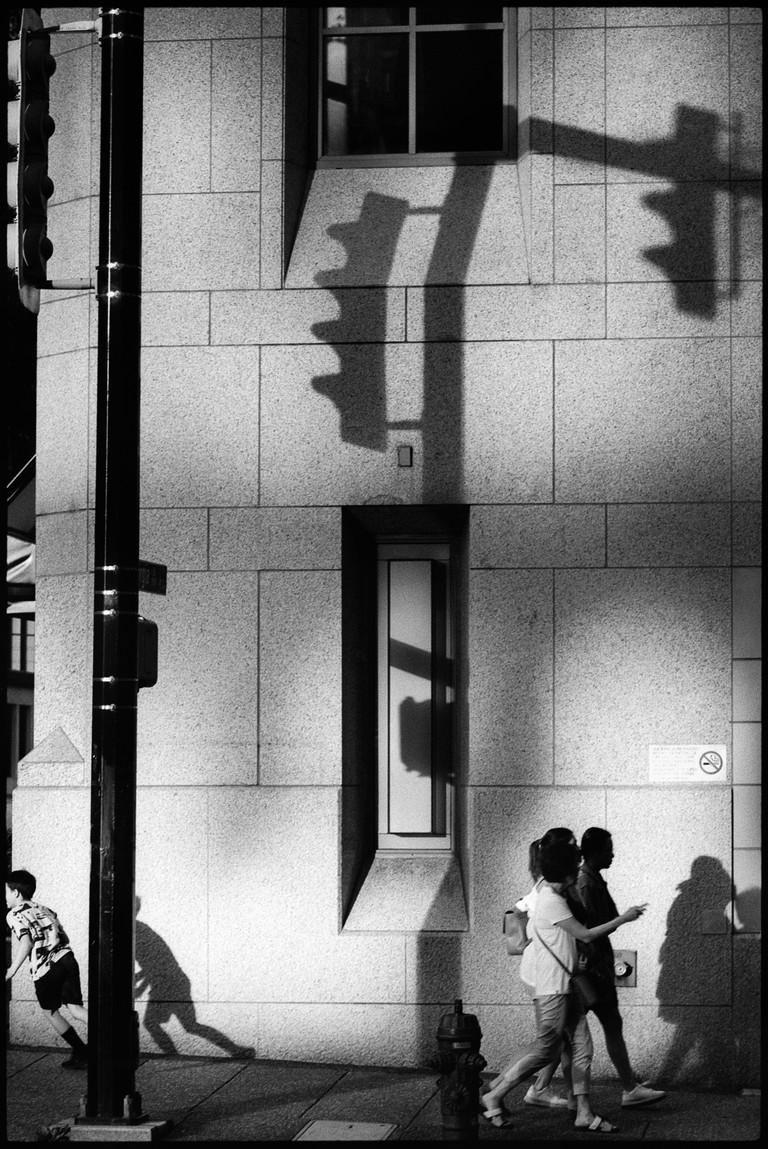 A child scurries around the corner of a building as long shadows fall.