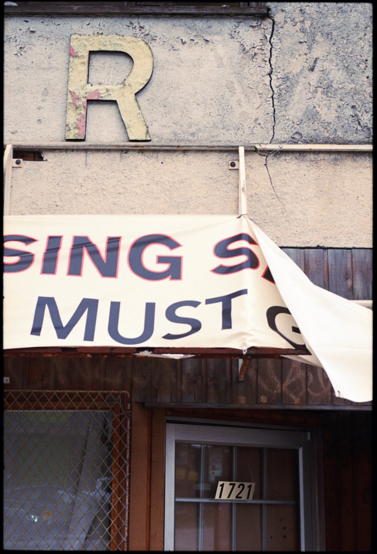 A weathered storefront seems incapable to collecting its words, merely declaring random letters.
