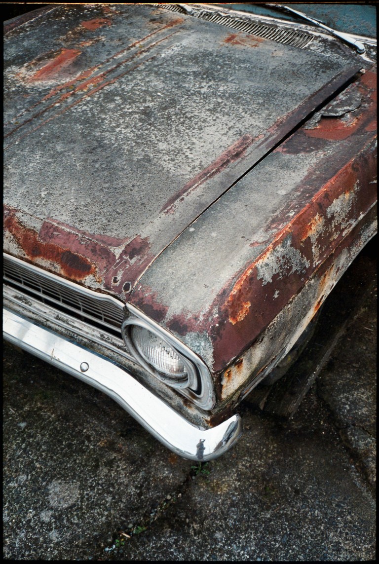 A vehicle sits parked, it's rusted and patinated suggests a hard life under the Vancouver rain.