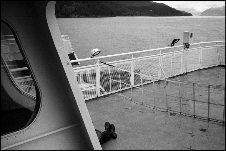 A passenger scans the horizon on the top deck of the ferry.