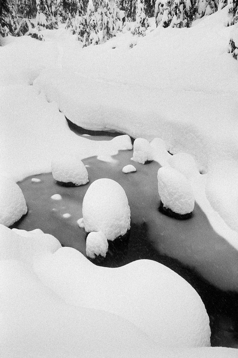 Snow domes on rocks in a cold stream.