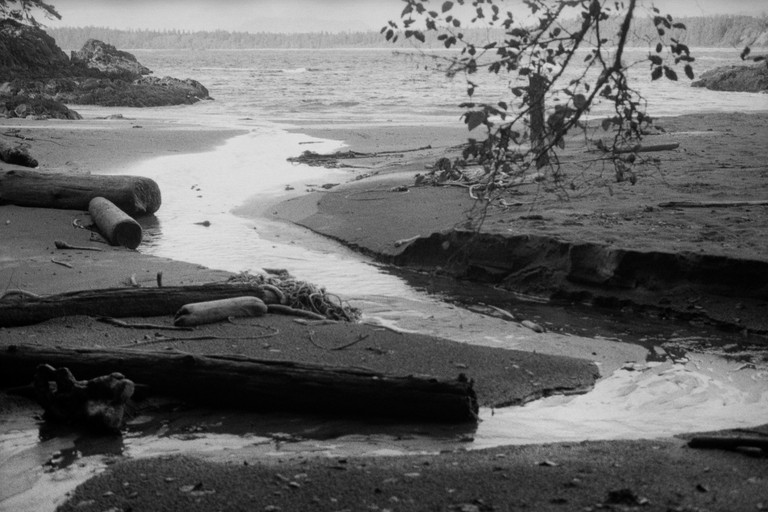 A stream meanders across a beach to the ocean.