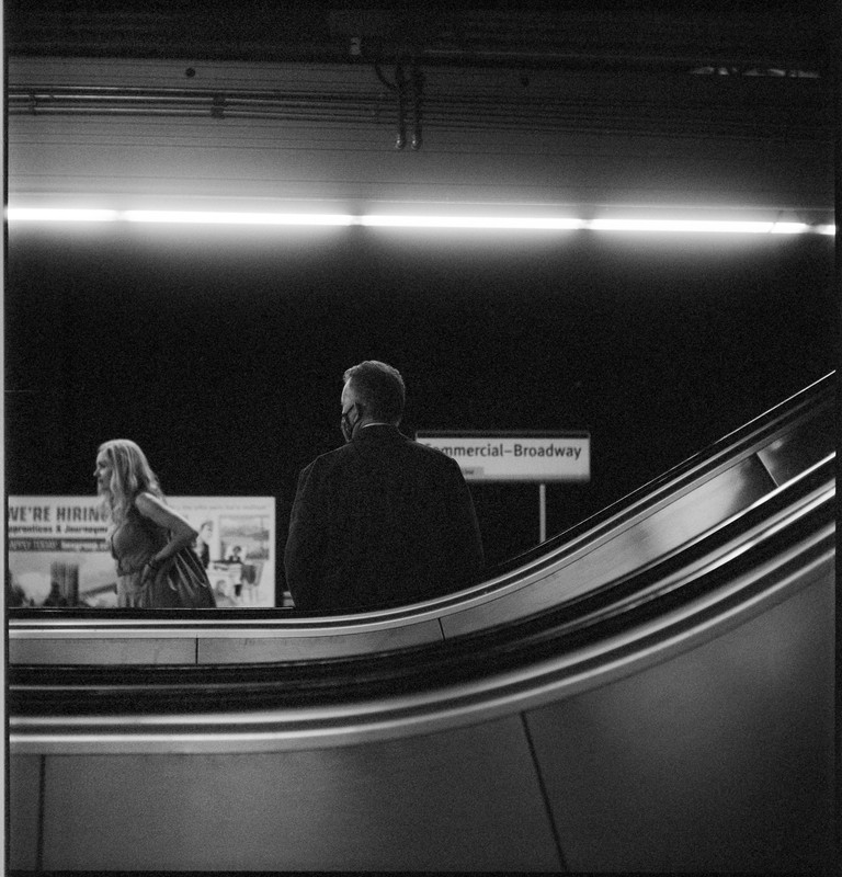 A man waiting for a train eyes a woman walking down the platform.